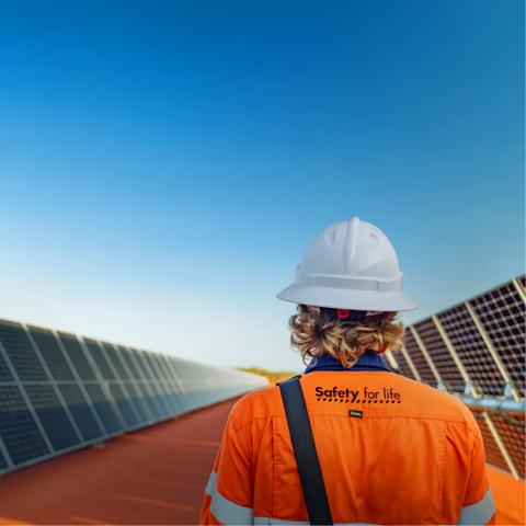 Close-up shot of a worker in uniform's back on a rooftop.