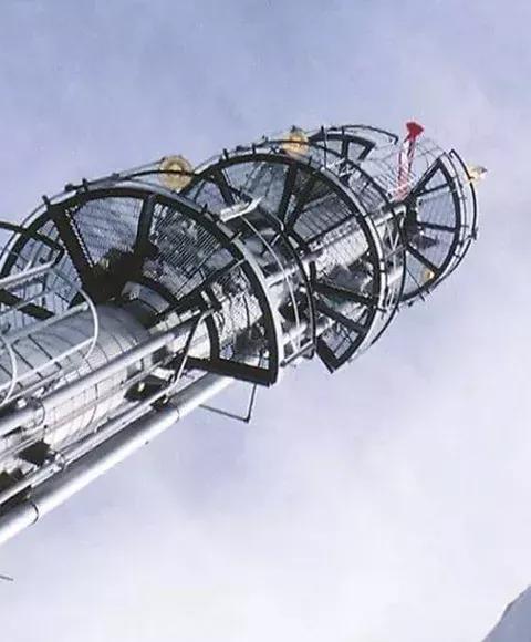 Ground view of a refinery tower under a cloudy sky.