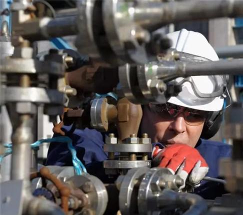A worker with a safety hat on manipulating a pipeline system