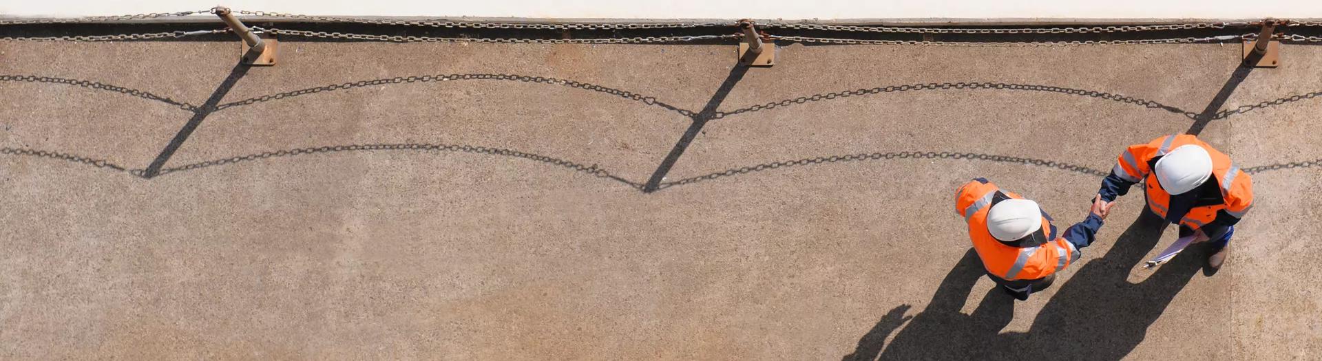 Overhead view of Caucasian technicians shaking hands near water