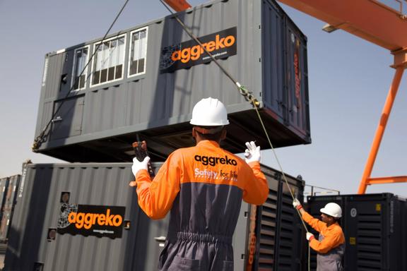 Technicians moving gas generators with crane