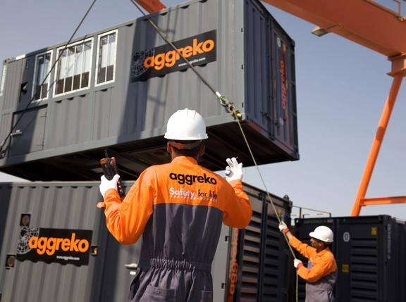 Technicians moving gas generators with crane