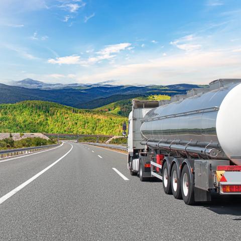 Fuel truck on a picturesque road. A silver tank truck transports fuel.