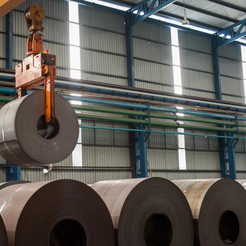 Image of crane loading of metal steel rolls.