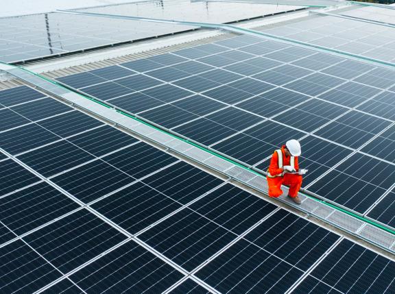 Electrical engineers are using laptops to monitor the operation of the solar rooftop. Renewable energy concepts.