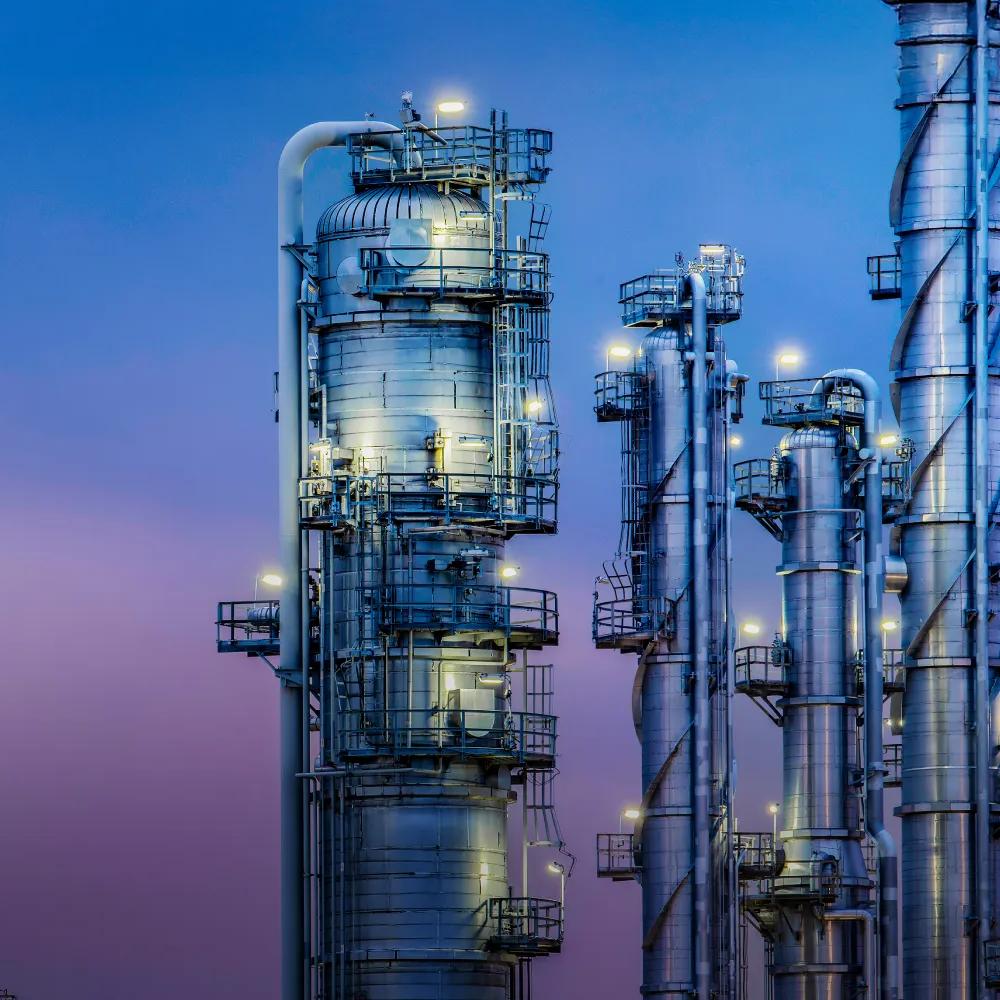 View of a refinery's towers under a blue, purplish sky