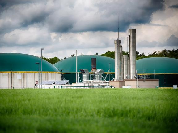 Wide angle shot of a modern biogas plant under a great cloudscape. Toned picture and vignette added.