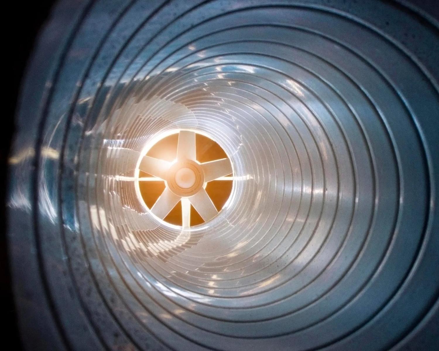 closeup view from inside the galvanized steel air duct on the exhaust fan in the background light, the front and back background is blurred with a bokeh effect