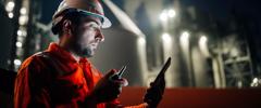 Caucasian man engineer using digital tablet working late night shift at petroleum oil refinery in industrial estate