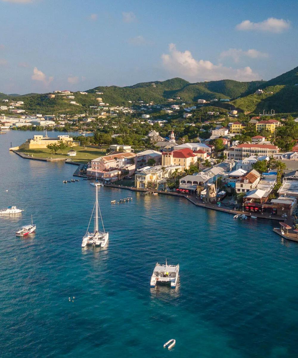 Aerial view of a Caribbean harbor with colorful buildings and docked boats.