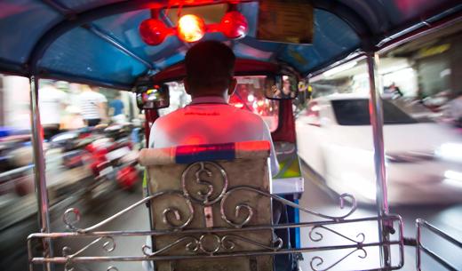 Tuk tuk driver speeding at night in Bangkok Thailand.