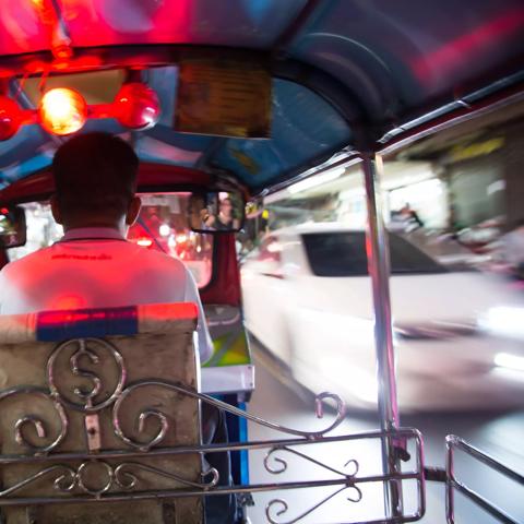 Tuk tuk driver speeding at night in Bangkok Thailand.