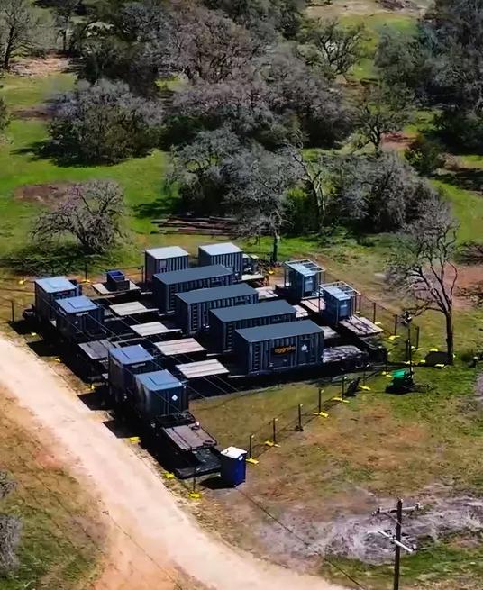 Ground view of wind turbine silhouettes against a pink sunset.  