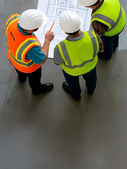 Aerial view of 3 workers in uniform looking at blueprints.  