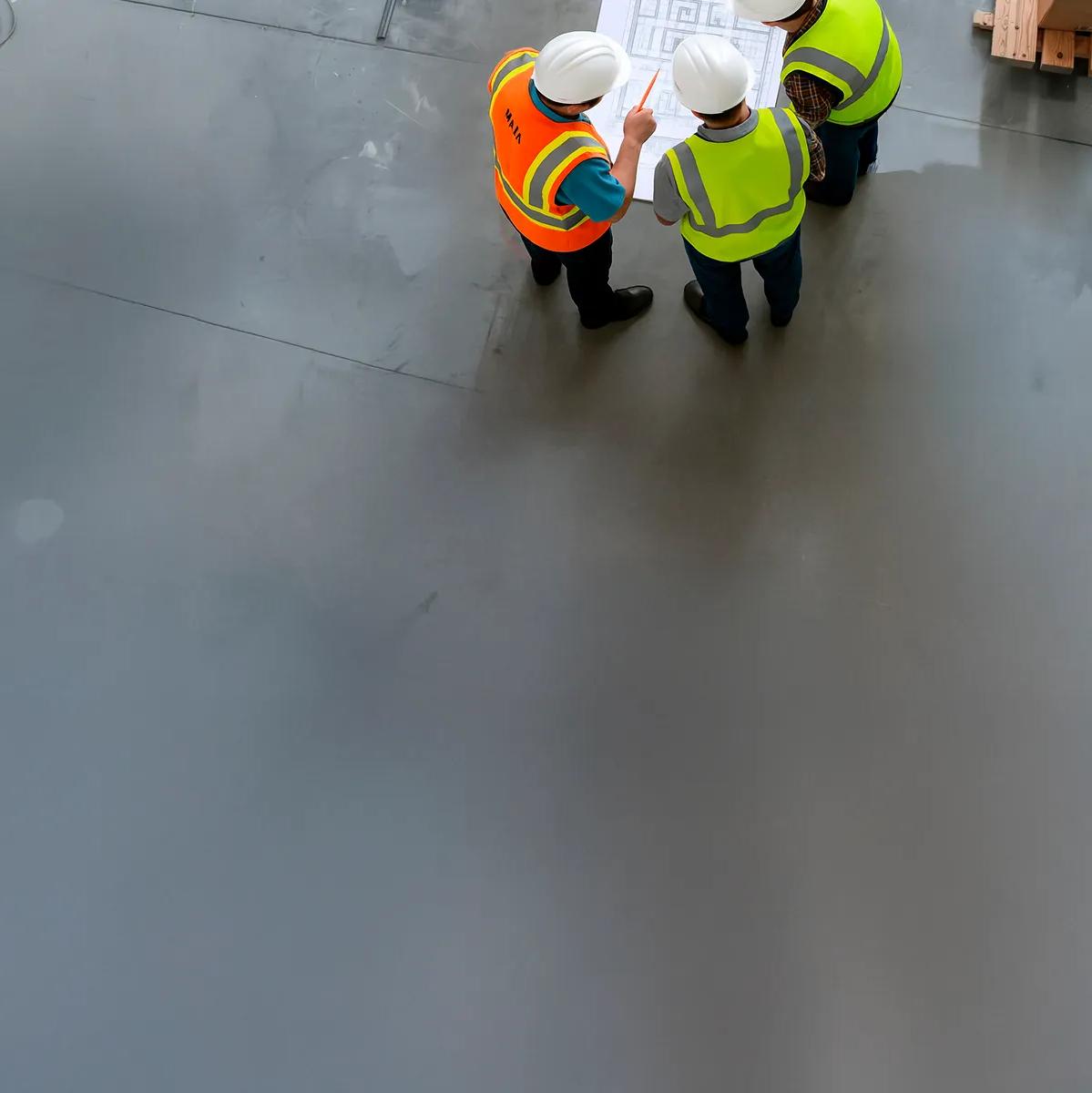 Aerial view of 3 workers in uniform looking at blueprints.  
