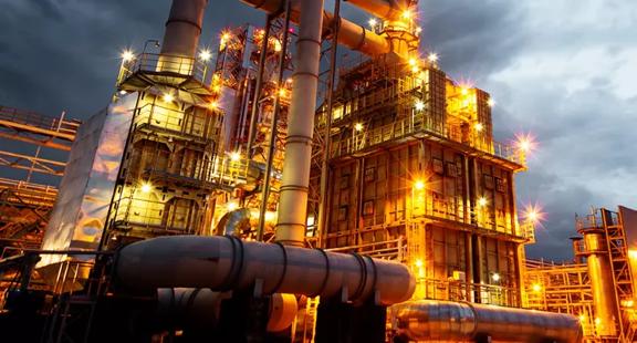 View of a lit up petrochemical refinery plant at night.