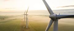 Aerial view of three wind turbines in the early morning fog at sunrise in the English countryside