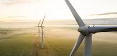Aerial view of three wind turbines in the early morning fog at sunrise in the English countryside